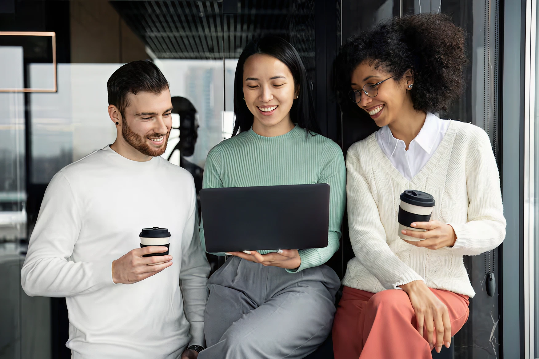 Three colleagues looking at a laptop together