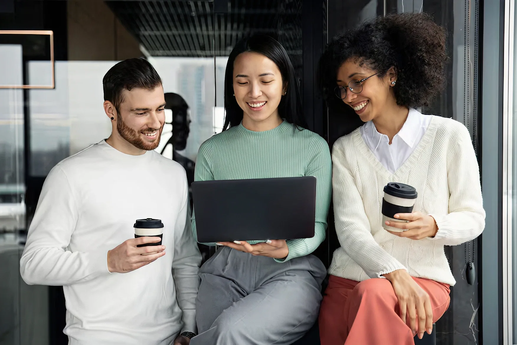 Three colleagues looking at a laptop together
